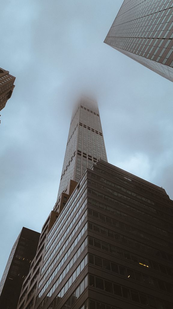 A towering New York City skyscraper piercing through the fog, showcasing urban architecture.